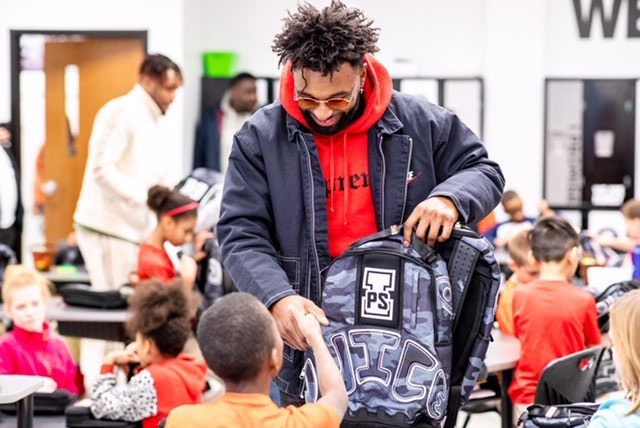 Jarvis Landry handing a customized backpack to a student